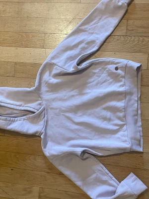 Ljuslila hoodie från Ü - Ljuslila hoodie från Ü med klassisk huva och ribbade muddar vid ärmslut och nederkant. Mjuk bomullskänsla och enkel design utan tryck eller mönster. Perfekt för dig som gillar stilrena plagg och vill ha något bekvämt att slänga på sig.