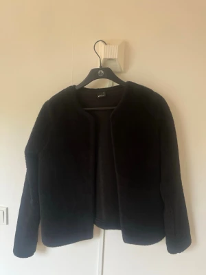 Svart teddy/päls jacka från Gina Tricot - Mysig svart teddyjacka från Gina Tricot i storlek M. Jackan har rund halsringning, raka ärmar och är tillverkad i ett fluffigt teddy-material som ger en trendig look. Perfekt för att hålla värmen och samtidigt se snygg ut.