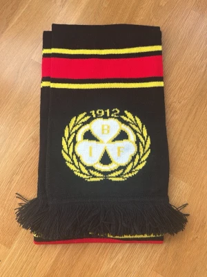 Brynäs IF halsduk  - Supporterhalsduk för Brynäs IF i svart med röda och gula ränder samt klubbens emblem. Halsduken har fransar i ändarna och är tillverkad i mjukt, stickat material. Pris kan diskuteras💕