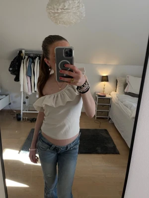 Vit offshoulder topp med volang - Säljer denna söta voffshoulder topp. Toppen är figurnära och axelbandslös, perfekt till jeans eller kjol. Enkel och stilren design som passar till många olika looks!💝