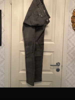 Grå jeans från G-Star RAW - Säljer ett par grå jeans från G-Star RAW i storlek 36. Jeansen har klassisk femficksdesign, raka ben och synliga sömmar. Materialet är denim i bomullsblandning och färgen är en snygg, mörkgrå nyans.