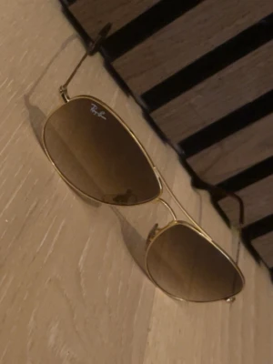 Ray-ban solglasögon  - Snygga solglasögon från Ray-Ban med guldfärgad metallbåge och bruna tonade glas. Perfekta nu till sommaren inför soliga dagar och passar till det mesta. Tveka inte på att skriva för minsta fråga eller fundering. Bättre pris vid snabba affärer.