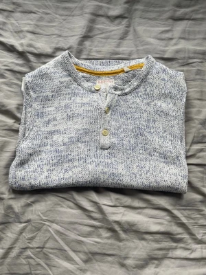 Henley  - Snygg långärmad henleytröja från Esprit i blåmelerad bomull. Tröjan har rund halsringning och tre knappar framtill. Perfekt för en avslappnad och stilren look. Mjuk och skön kvalitet med diskret logomärke nertill. 