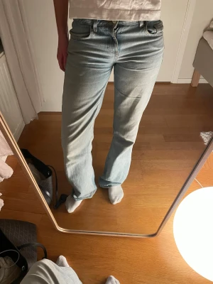 Ljusblå jeans  - Säljer ett par ljusblå jeans med baggy passform och låg midja. Jeansen har klassiska fem fickor och stängs med dragkedja och knapp. Perfekta till en avslappnad stil och passar till det mesta. Materialet är mjukt denim i bomull.