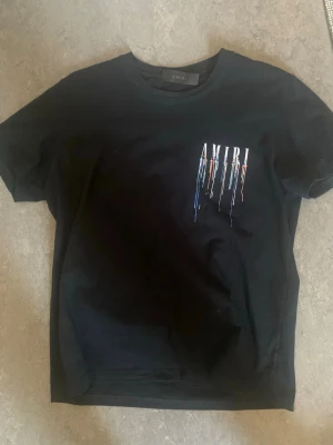 Svart AMIRI t-shirt  - Säljer en svart t-shirt från AMIRI med coolt tryck framtill och stort AMIRI-tryck på ryggen. Den passar både S/M