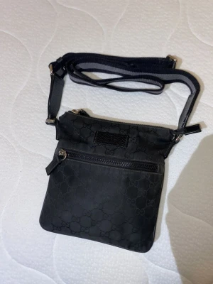 Gucci väska nylon svart - Säljer min gucci väska då jag aldrig använder den. Äkta såklart, perfekt skick. Meddela mig om det finns frågor,  kan mötas i Stockholm annars gäller frakt. 