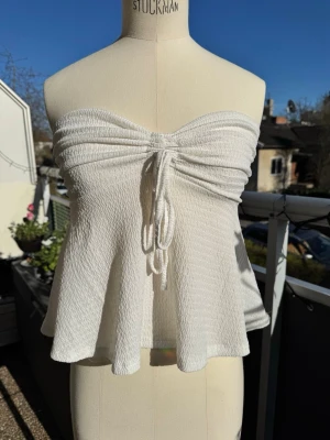 Vit bandeau tubtopp med snörning - Supersöt vit bandeau tubtopp med snörning framtill. Stretchigt material. Perfekt för varma dagar. Smart strandplagg över bikinin när man går & köper glass 🍦