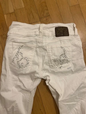 Vita jeans med strassdetaljer Bik Bok - Snygga Lågmidjade vita jeans från Bik Bok med detaljer på bakfickorna. Midjemått är 37cm. De var köpta från en secondhand affär 