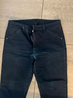 Mörkblå jeans från tasty  - Säljer ett par mörkblå jeans från tasty med klassisk femficksdesign och raka ben. Jeansen har snygga detaljer och ett diskret märke på bakfickan. Materialet är slitstark denim, ca storlek w:38 L:28