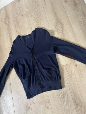 Mörkblå cardigan från Polo Ralph Lauren - Snygg marinblå cardigan som är perfekt nu under våren! Den är i ett mycket bra skick och har inga defekter alls. Den är i ett riktigt skönt material och i storlek S. Bara att höra av er vid frågor! 