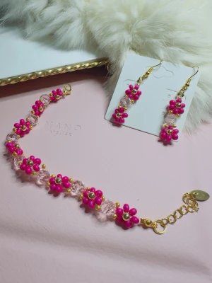 Sidawi Atelier armband med rosa pärlor - Armband från Sidawi Atelier med klara och rosa pärlor, dekorerat med små guldfärgade detaljer. Designen har blommönster av pärlor och ett justerbart guldfärgat lås. Perfekt för dig som gillar färgstarka accessoarer och unika smycken. Handgjorda 