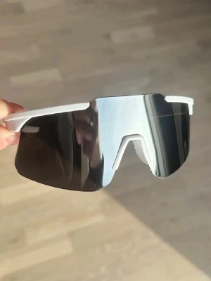 Solglasögon / aktivitetsglasögon  - Säljer ett par helt nya riktigt snygga solglasögon med vit båge och stora spegelblanka shield-linser. UV-skydd och passar både kvinnor och män. 