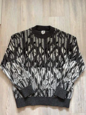 Mönstrad stickad tröja från Polar Skate - Säljer en stickad tröja från Polar skate med grafiskt mönster i svart, grått och vitt. Tröjan har rund halsringning, ribbade muddar och en avslappnad passform. Storlek 1 ~ Small. Använd två gånger