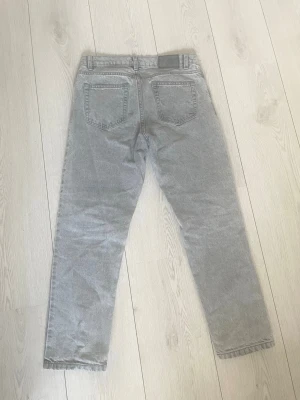 Grå raka jeans från Grunt - Säljer ett par grå jeans från grunt med rak passform och klassisk femficksdesign. Jeansen har bälteshällor och stängs med dragkedja och knapp. Perfekta för en avslappnad och stilren look.Med storlek 26