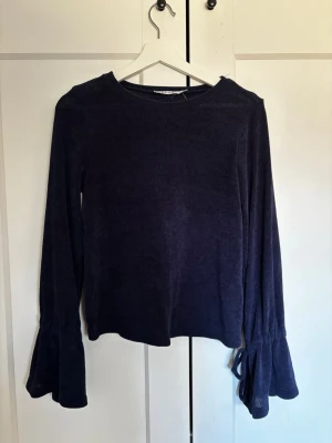 Mörkblå tröja med knytärmar - Mörkblå långärmad tröja från NAKD med rund halsringning och unika vida ärmar som avslutas med knytband. Tröjan har en enkel, rak passform och är tillverkad i ett tunt, stickat material som känns mjukt mot huden. Perfekt för dig som gillar stilrena detaljer. Kommer inte till användning så jättefint skick. Pris kan diskuteras och bara att skriva vid frågor/för fler bilder💗