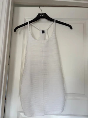 Vit ribbad linne med smala band - Vitt långt och ribbat linne med smala axelband. 