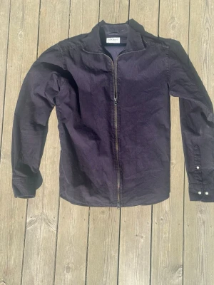 Svart overshirt med dragkedja - Stilren svart overshirt Perfekt att bära som lager över t-shirt eller tröja.