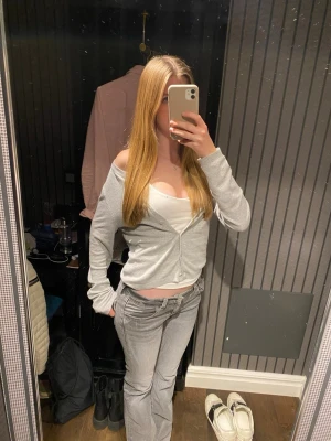 Gråa jeans med detaljer - Säljer ett par gråa jeans från Gina Tricot  i storlek 170, med snygga dekorativa fickor bak och klassisk femficksdesign. Jeansen är bootcut och har låg midja, perfekt för dig som gillar en cool och avslappnad stil. Materialet är mjukt och stretchigt denim.