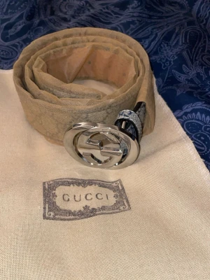 Beige Gucci bälte med silverdetalj - Snyggt beige bälte från Gucci med klassiskt GG-spänne i silver. Bältet har en stilren design och är tillverkat i skinn med präglad logotyp på insidan. Perfekt accessoar för att lyfta din outfit.