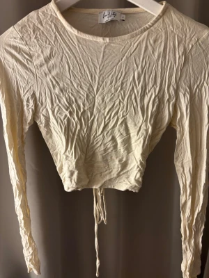 Gul topp - Säljer denna supersöta ljusgula långärmade toppen från NA-KD, med öppen rygg & knytning😍 tycker den är så fin men kommer aldrig till användning därav är den lite skrynklig (kan stryka innan den skickas) 