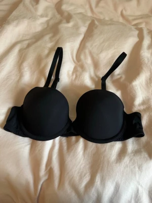 Klassisk svart bh med bygel - Snygg svart bh med bygel för extra stöd. Justerbara axelband och klassisk hakknäppning bak. Tillverkad i mjukt och stretchigt material som ger en bekväm passform. Perfekt för dig som vill ha en enkel och stilren bh! Bra som T-shirt bh och basplagg🩷Storlek 70A, aldrig använd! 