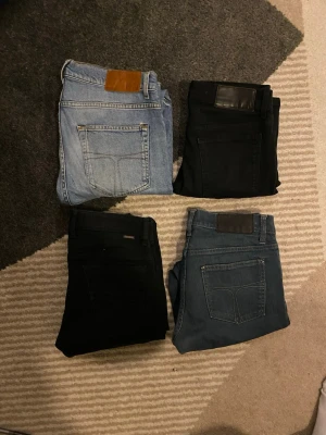 Fyra par jeans i olika färger - Säljer fyra par jeans i olika färger: ett par ljusblå, två par svarta och ett par mörkblå. Klassisk femficksmodell med raka ben och läderpatch bak i midjan. Perfekta för dig som vill ha flera stilar att välja mellan.