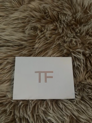 Vit plånbok från Tom Ford - Snygg vit plånbok från Tom Ford i slimmad design med silverfärgad dragkedja och TF-logga framtill. Tillverkad i slätt läder och levereras i originalask. Perfekt för kort och sedlar.