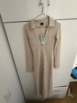 Långklänning Gina Tricot - Strandklänning/ långklänning i nytt skick. Klänningen har långa ärmar och är tillverkad i ett mjukt stickat material som ger en avslappnad men ändå stilren look. Perfekt för dig som gillar en enkel men chic stil.
