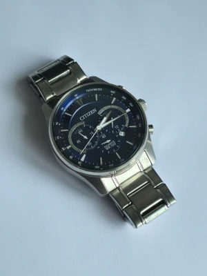 Citizen kronograf Herrklocka - Stilren kronografklocka från Citizen med silverfärgad länk i rostfritt stål och mörkblå urtavla. Klockan har flera små urtavlor, tachymeter och datumvisning. Perfekt accessoar för dig som gillar klassisk och sportig stil. Nypris: 1500-1700, vårat mycket lägre pris ligger på endast 1199:- 