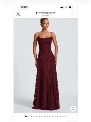 Vinröd långklänning  - Elegant vinröd långklänning med blommigt mönster, smickrande passform och öppen rygg med snörning. Helt oanvänd. 
