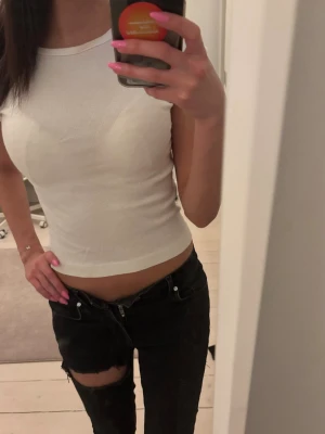 Vit ribbad ärmlös linnetopp - Snygg vit ribbad linnetopp med croppad passform. Toppen är ärmlös och har en rund halsringning, perfekt för varma dagar eller som layering-piece. Enkel och stilren design som passar till det mesta.