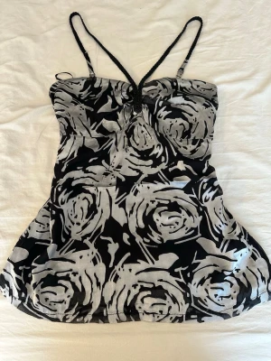 Svart och silver blommig linnetopp - 1990s Y2K-style black and white rose print halter top Remmarna är gjorda av svart läder. De flagnar lite, men det syns inte eftersom de redan är svarta. 