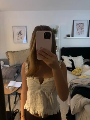 Vit spetsdetaljerad linnetopp - Söt vit linnetopp med spetsdetaljer och volangkant. Toppen har knappar framtill, breda axelband med volanger och en lätt croppad passform. Jättesöt💕