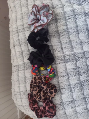 6-pack scrunchies i olika färger och mönster - Säljer ett set med sex scrunchies i olika färger och mönster: en blå med rosa blommor och brun kant (handgjord) två svarta (varav en med dragkedja), en färgglad med mönster(handgjord), en leopardmönstrad och en i brun-svart leopardstil (vattentålig, bikinimaterial) Perfekta för att piffa till håret och ge din look en personlig touch.