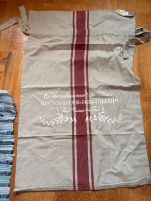 Stor säck tvättförvaring julsäck Notre Dame shabby chic lantlig stil  - Stor säck tvättförvaring julsäck Notre Dame shabby chic lantlig stil Gårdsromantik. Mått är cirka 97 x 60 cm. 100% bomull, krymper ca 5%. Fin till förvaring av ex tvätt eller julklappar. Eller som stolsskydd. Är aldrig använd. Ny pris cirka 350kr. Hämtas på Södermalm i Stockholm eller skickas till dig. Du bestämmer. Maila mig vid frågor.  Med vänlig hälsning, Fanny. 