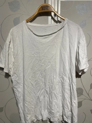 Vit basic t-shirt från KappAhl - En enkel vit t-shirt från lager 157 med rund halsringning och korta ärmar. Tillverkad i mjuk bomull, perfekt för en clean och avslappnad stil. Passar till allt och är ett måste i garderoben.