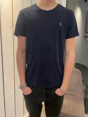 Ralph Lauren t shirt  - Klassisk mörkblå t-shirt från Ralph Lauren med liten broderad logga på bröstet. T-shirten har rund halsringning och korta ärmar. Tillverkad i mjuk bomull för en bekväm känsla och passar perfekt till jeans eller shorts.