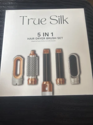 True Silk 5-i-1 hårstyler set - True Silk 5-i-1 hårstyler set med fem utbytbara borst- och stylinghuvuden. Setet innehåller fönmunstycke, rundborste, två locktillbehör och en paddelborste. Färgerna är svart, vit och koppar. Perfekt för att skapa olika frisyrer hemma.