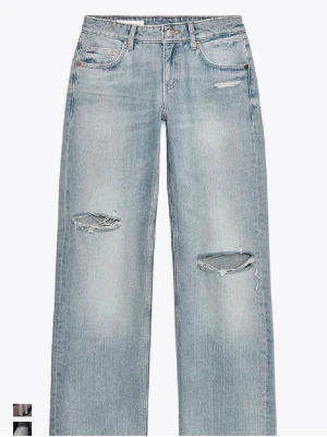 Ljusblå slitna raka jeans - Säljer ett par ljusblå jeans med raka ben och slitningar över knäna. Jeansen har klassisk femficksmodell, låg midja och är tillverkade i denim. Perfekta för en avslappnad och trendig look. Jeansen är väldigt trendiga och helt slutsålda!