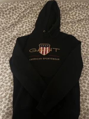 Svart hoodie från GANT med fräscht tyg. Ny, äkta och passar till allt! - Säljer en svart hoodie från GANT. Billigt pris och supervärt!