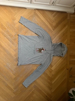 Grå hoodie Polo Bear Ralph Lauren - Säljer en grå hoodie från Ralph Lauren med Polo Bear-tryck framtill där björnen rider häst i polotröja. Hoodien har dragsko i huvan och är gjord i mjukt bomullsmaterial. Perfekt för dig som gillar streetwear och klassiska prints. Den är äkta, aldrig använt och pris kan diskuteras!
