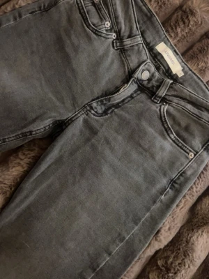 Gråa skinny jeans från junkyard - Säljer ett par gråa skinny jeans från  junkyard med klassisk femficksdesign och coola bakfickor med zigzag-detalj. Jeansen har normal midja och är tillverkade i stretchigt denimtyg för skön passform.