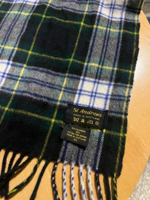Rutig halsduk från St Andrews - Snygg rutig halsduk från St Andrews i klassiskt skotskt mönster med färgerna mörkgrön, blå, vit och gul. Halsduken är tillverkad i 100% kashmir och har fransar i ändarna. Perfekt accessoar för att lyfta din outfit med en tidlös look. Priset är inte huggit i sten