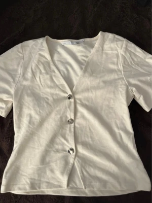 Vit v-ringad topp från 157 - Säljer en enkel och stilren vit topp från 157 med v-ringning och tre knappar framtill. Fint skick och pris kan diskuteras🤍