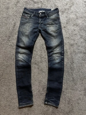 Diesel jeans - Snygga mörkblå slim fit jeans från G-Star RAW med slitna detaljer och klassisk femficksdesign. Jeansen har en lätt tvättad look och diskreta logodetaljer vid myntfickan. Perfekta för en trendig och avslappnad stil.