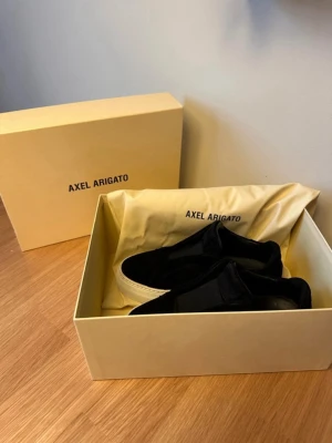Svarta sneakers från Axel Arigato - Stilrena svarta sneakers från Axel Arigato med tjock vit sula och minimalistisk design. Skorna är i mocka och har diskret logga på sidan. Kommer med originalkartong och dustbag. Använda 5ggr. Nypris 2950