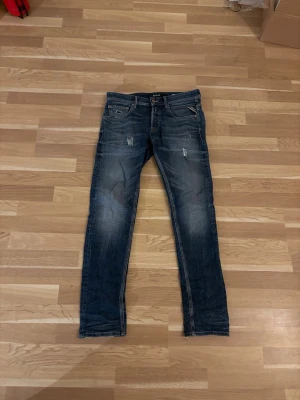 Mörkblå replay jeans med slitningar - Säljer ett par mörkblå slim fit jeans med snygga slitningar och tvättade detaljer på låren och knäna. De är i okej skick, Strlk 28, nypris 1 200kr. Tveka inte på att höra av dig vid frågor!