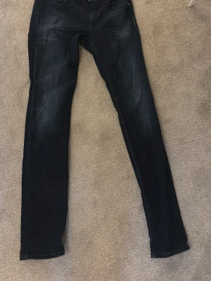 Mörkblå slim fit jeans - Snygga mörkblå slim fit jeans från replay med lätt slitna detaljer och klassisk femficksdesign. Jeansen har smal passform och är perfekta för en trendig och avslappnad look. Materialet är mjukt och stretchigt för extra komfort.