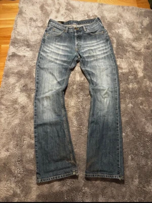 Bootcut jeans Lee - Säljer ett par riktigt snygga bootcut Lee jeans med vintage wash. Jeansen har lagningar i yttersömmen nere vid benöppning. Måtten är följande: midja 37 cm, innerbenslängd 83 cm, totala längd 109 cm, benöppning 23 cm och lår 28 cm.
