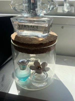 Versace Bright Crystal parfymflaska - Säljer en elegant parfymflaska från Versace Bright Crystal. Flaskan är genomskinlig med en stor, diamantformad kork i plast och har en stilren, lyxig design. Märket och doftnamnet står tydligt på framsidan. Perfekt för dig som gillar exklusiva dofter och snygg inredning. 50 ml från början och hur mycket som är kvar ser ni🤗🤗